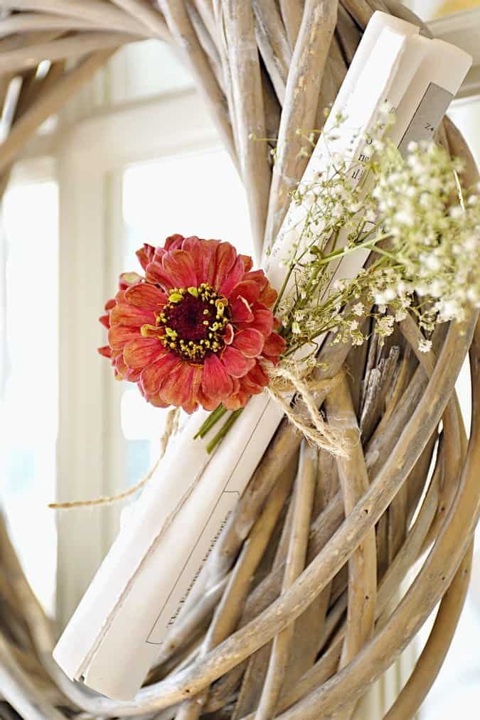 Woven wooden wreath with book pages and flowers.