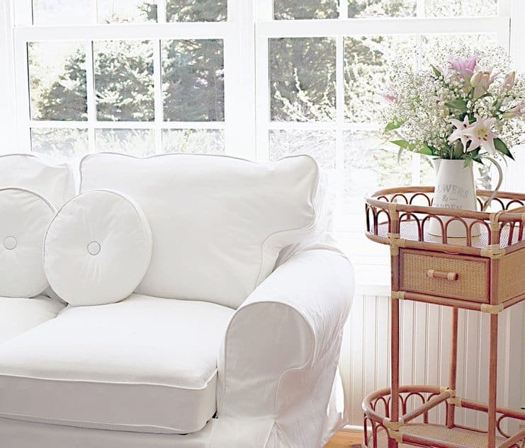 White loveseat with vintage wicker beverage cart with pink flowers.