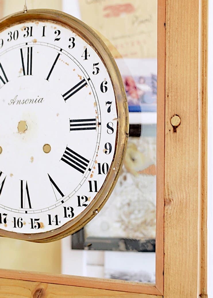 Vintage clock face on glass door on wooden vintage hutch.