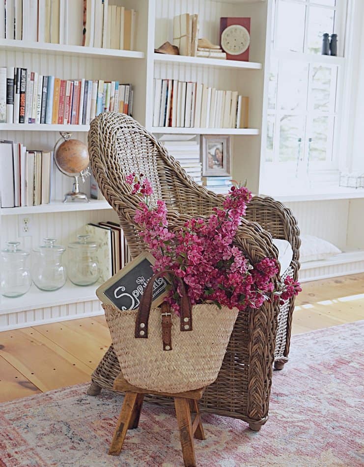 Decorated bookshelves, wicker chair flowers in a basket.