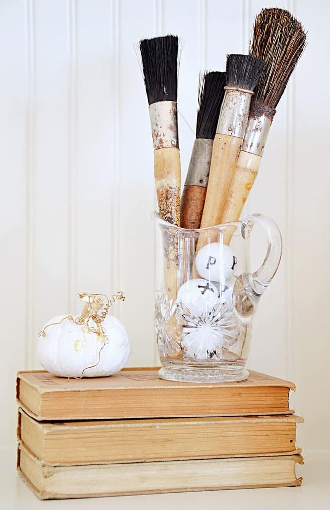 Vintage paintbrushes, letter balls, books and white pumpkin