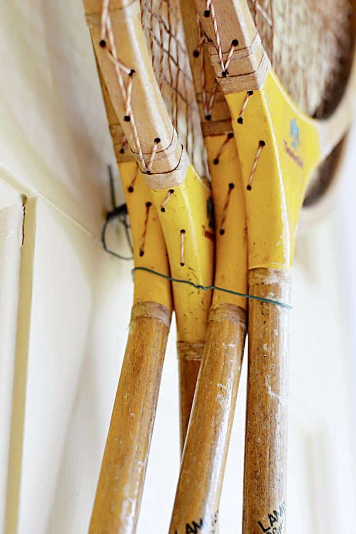 4 Vintage badminton racquets hanging with wire on front door.