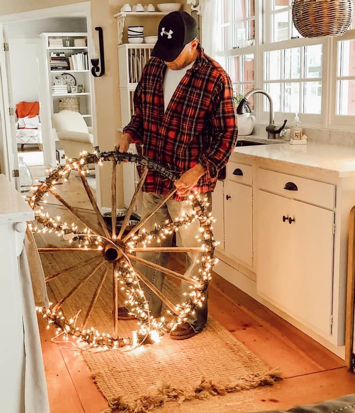 A man is decorating a wagon wheel with lights for home decor.