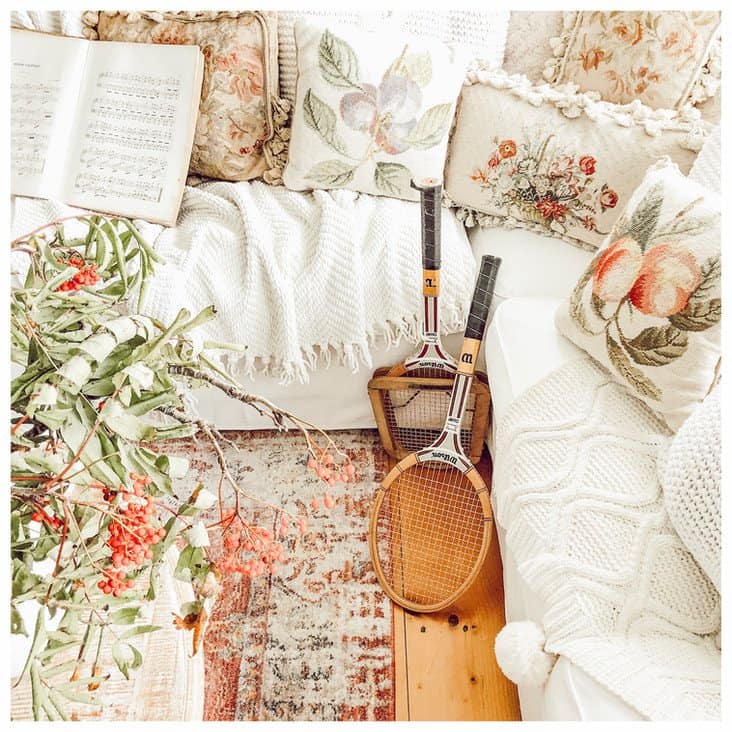 A vintage living room with tennis rackets as decor and embroidery pillows.