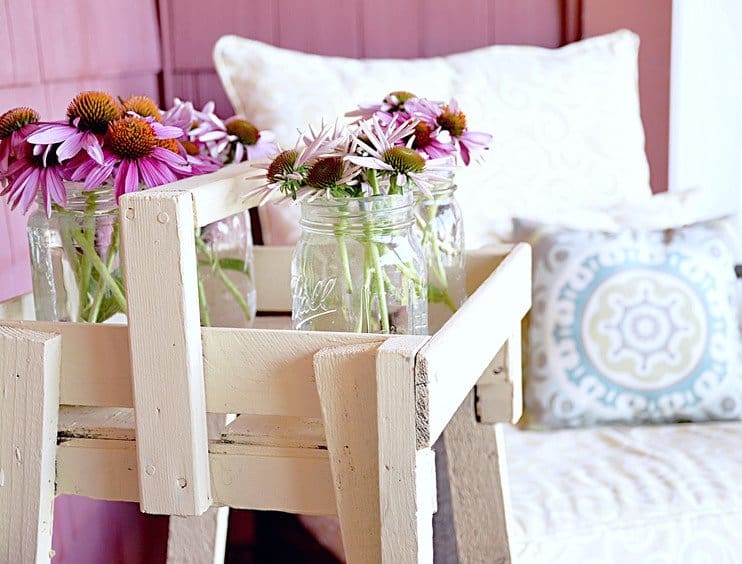 Vintage flower stand with mason jars and flowers on the porch.