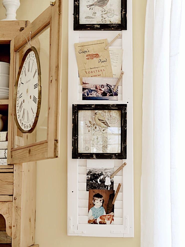 Vintage painted shutter with nostalgia and vintage family photos next to vintage clock face on vintage dining hutch.