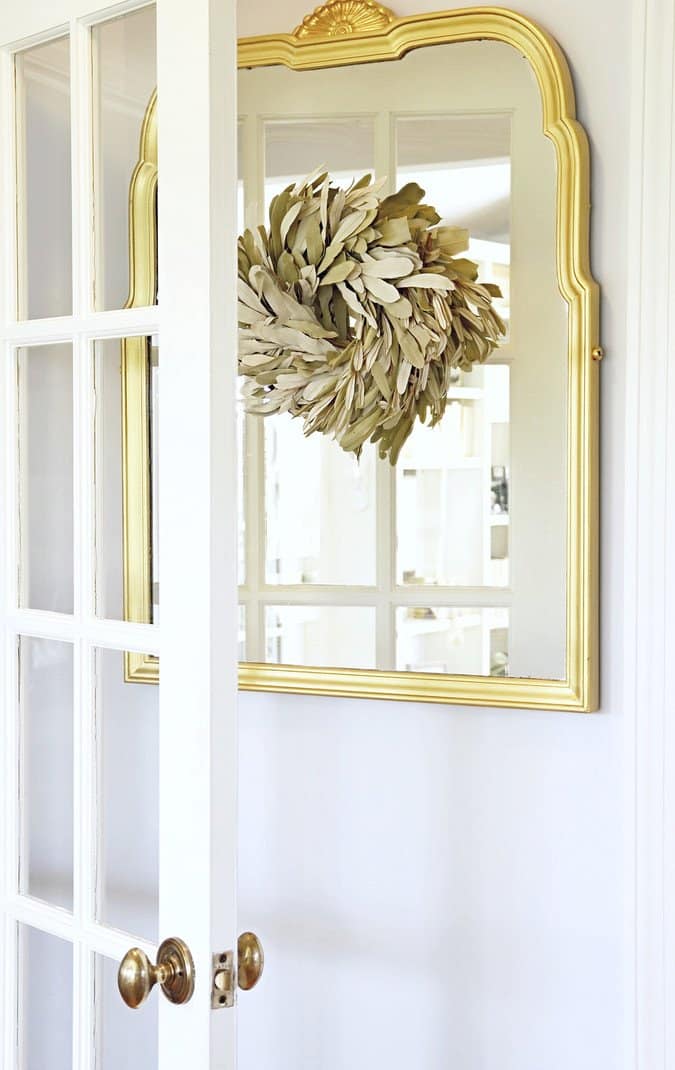 Vintage gold mirror with neutral wreath.