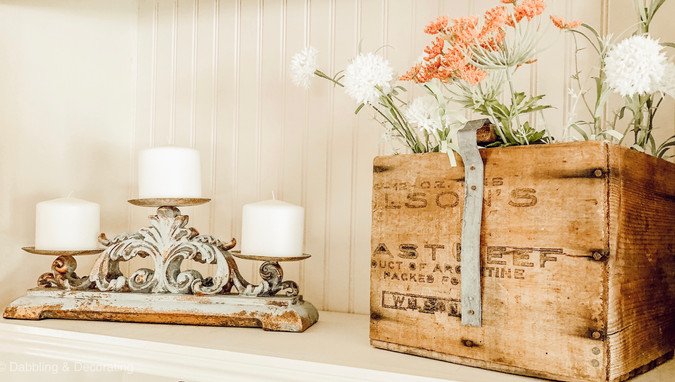 Vintage crate with flowers and candle holder on bookshelf