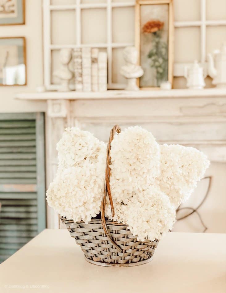 blue basket with white hydrangeas and a mantel.