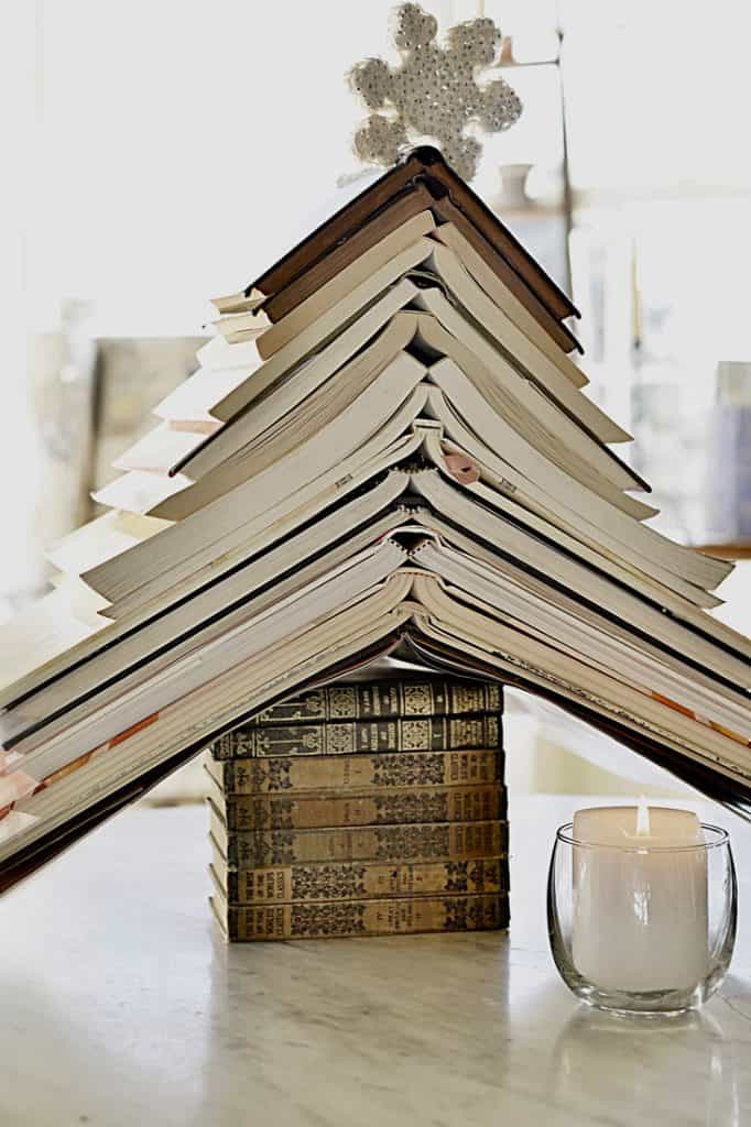 A thrifty decor idea for decorating a table during Christmas, featuring a Christmas tree made out of books.