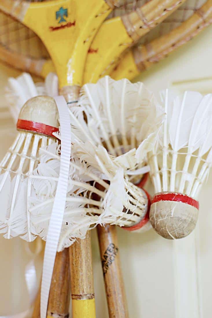 4 Vintage badminton racquets with 5 vintage birdies wrapped around the racket's neck.