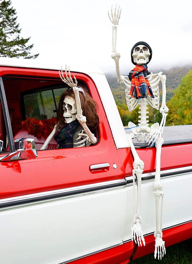 Halloween skeletons in the fog in vintage truck.