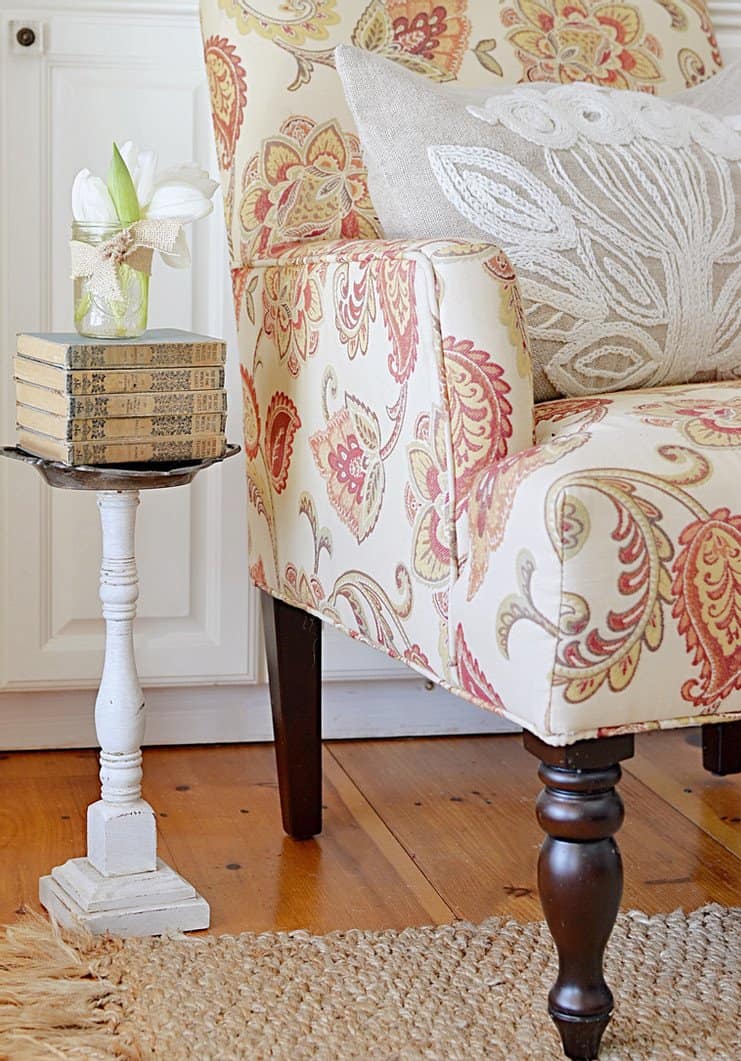 Vintage books with tulips in a jar next to a chair.