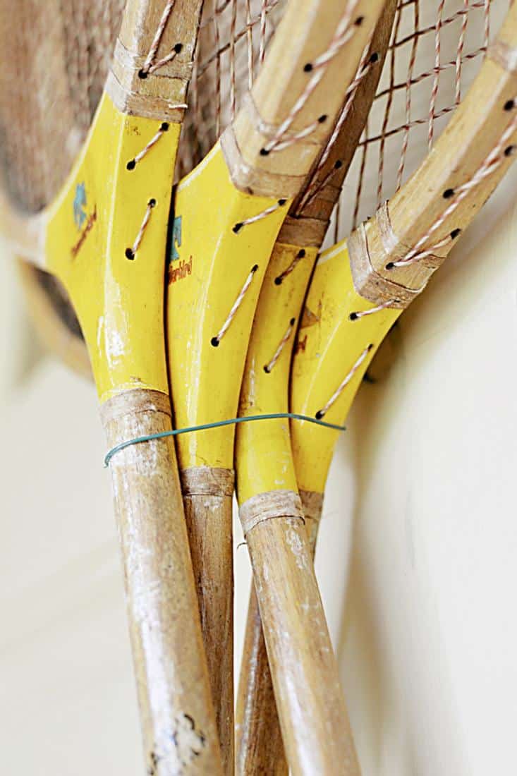4 Vintage badminton racquets hanging with wire on front door.