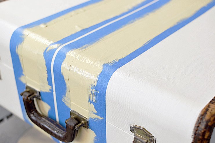 Vintage suitcase with painters tape with yellow stripes.