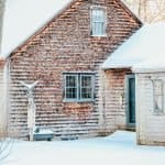 A house covered in snow in front of a brick building
