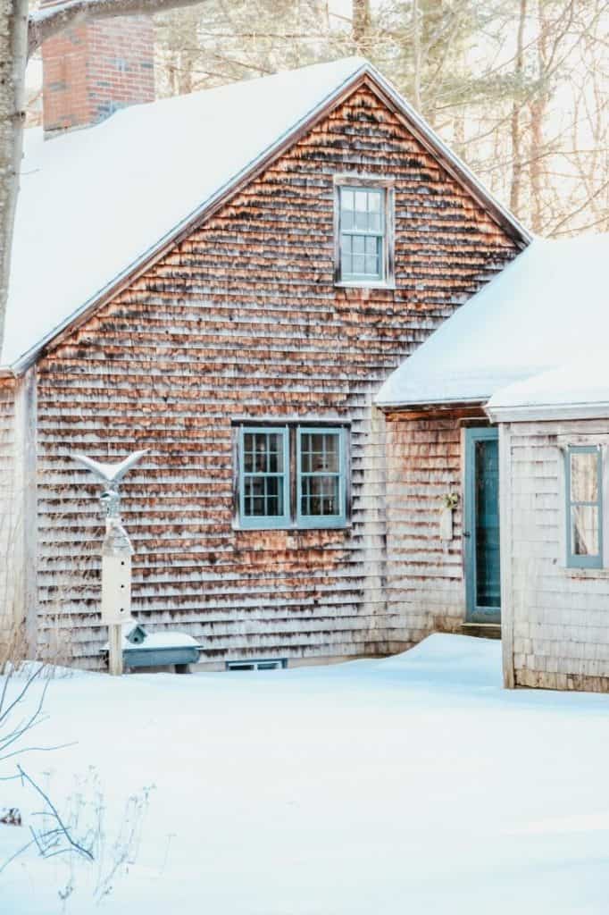 A house covered in snow in front of a brick building