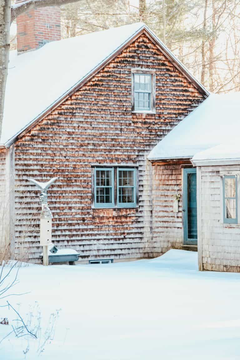 A house covered in snow in front of a brick building