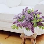 Decorate your home with a thrifty touch by placing beautiful purple lilacs in a white vase on a wooden stool.