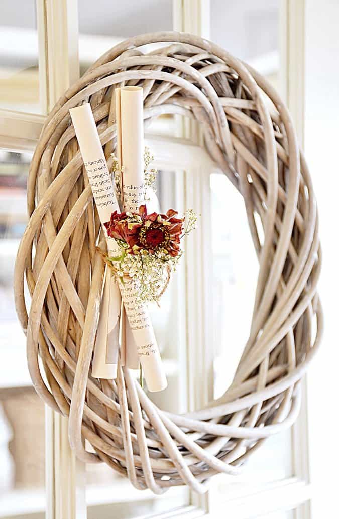 Wooden wreath with book pages and flowers.