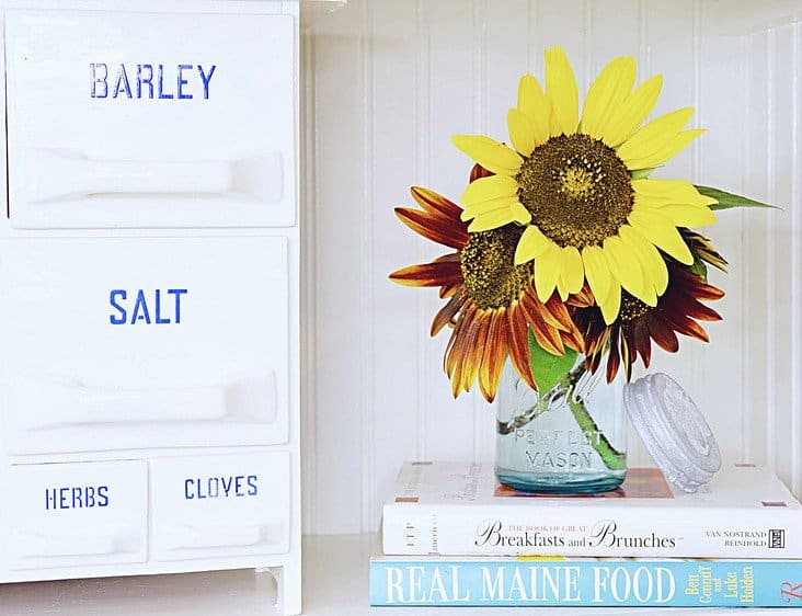 Vintage spice rack in kitchen with flowers.