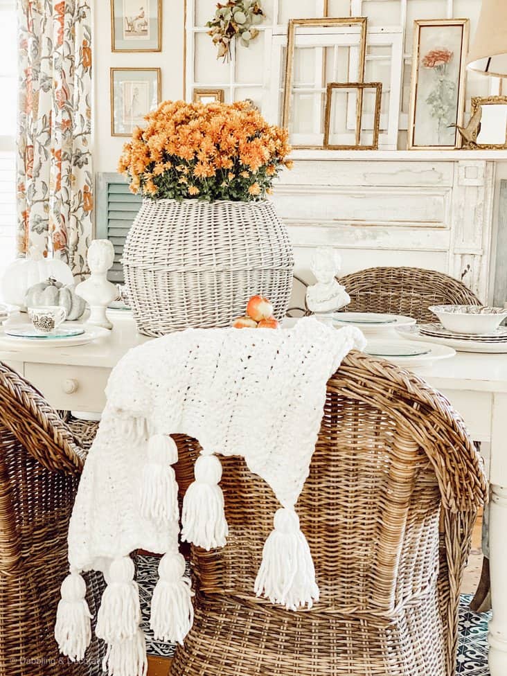 Thanksgiving Dining Room Set with Thanksgiving centerpiece of orange mums in white wicker basket in Farmhouse style dining room.