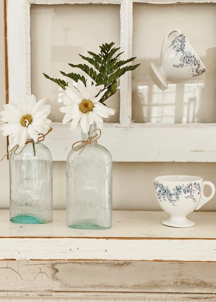 salvaged window with teacups and bottles.