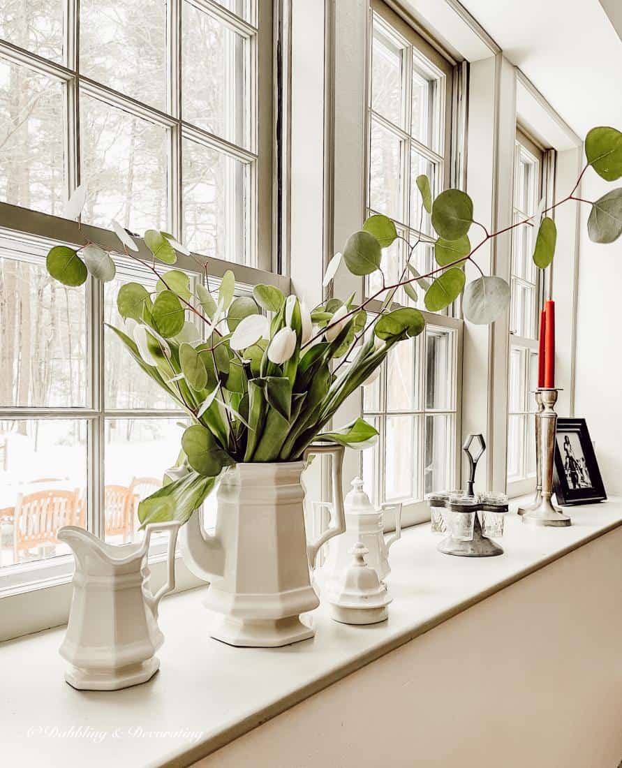 Vintage white tea set with white tulips and greenery as window sill decor.