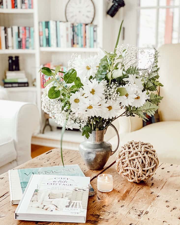 bouquet of flowers, books, candle and rope ball on small home library coffee table.