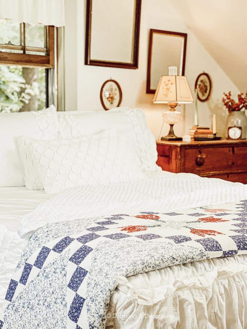 Quilt on top of white decorated bed with vintage dresser.