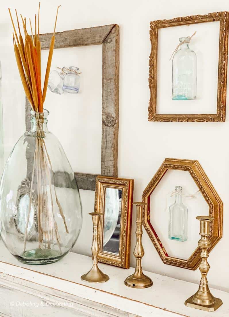 gold frames and rustic wood frame with hanging bottles on wall display.