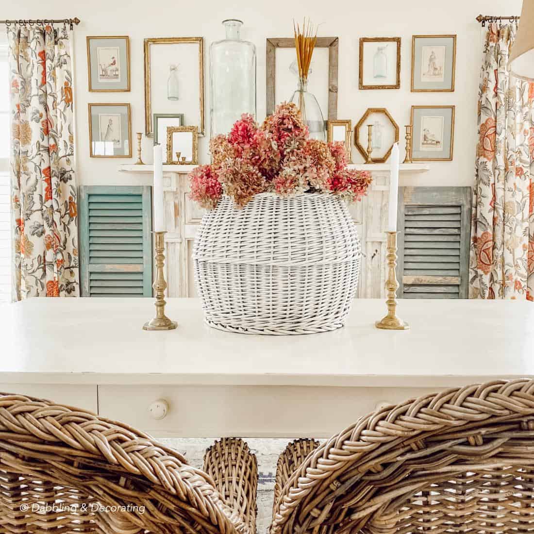 Dining room table with hydrangeas centerpiece in front of gold frames wall display.