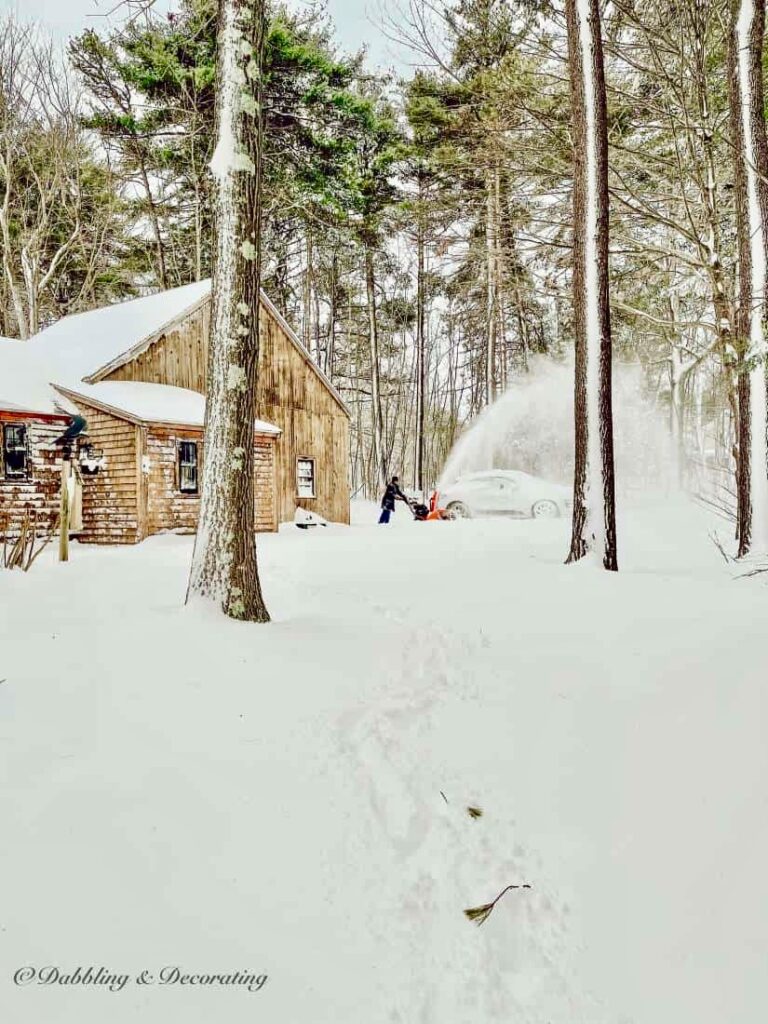 Man snowblowing how cottage in Maine.