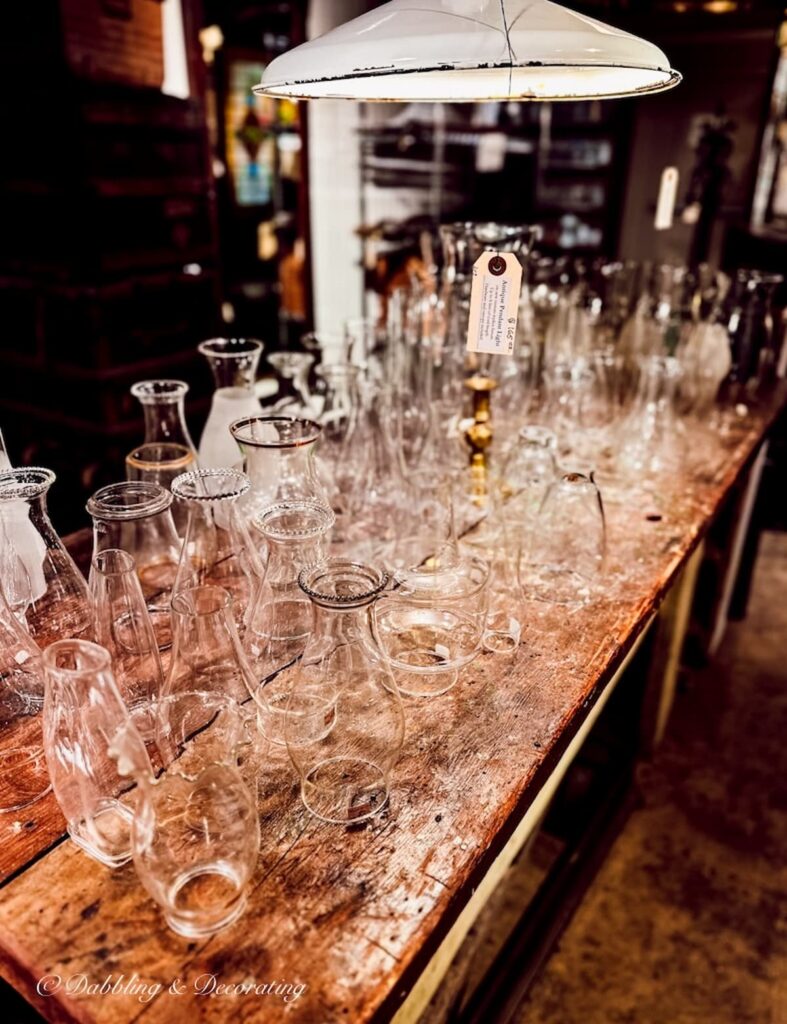 Inside Windham Antique Center in Bellows Falls, Vermont a large table filled with hurricane lamp glass chimneys.