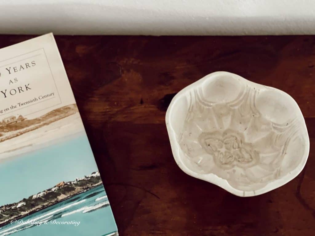 Ironstone mold and coastal book on antique table.