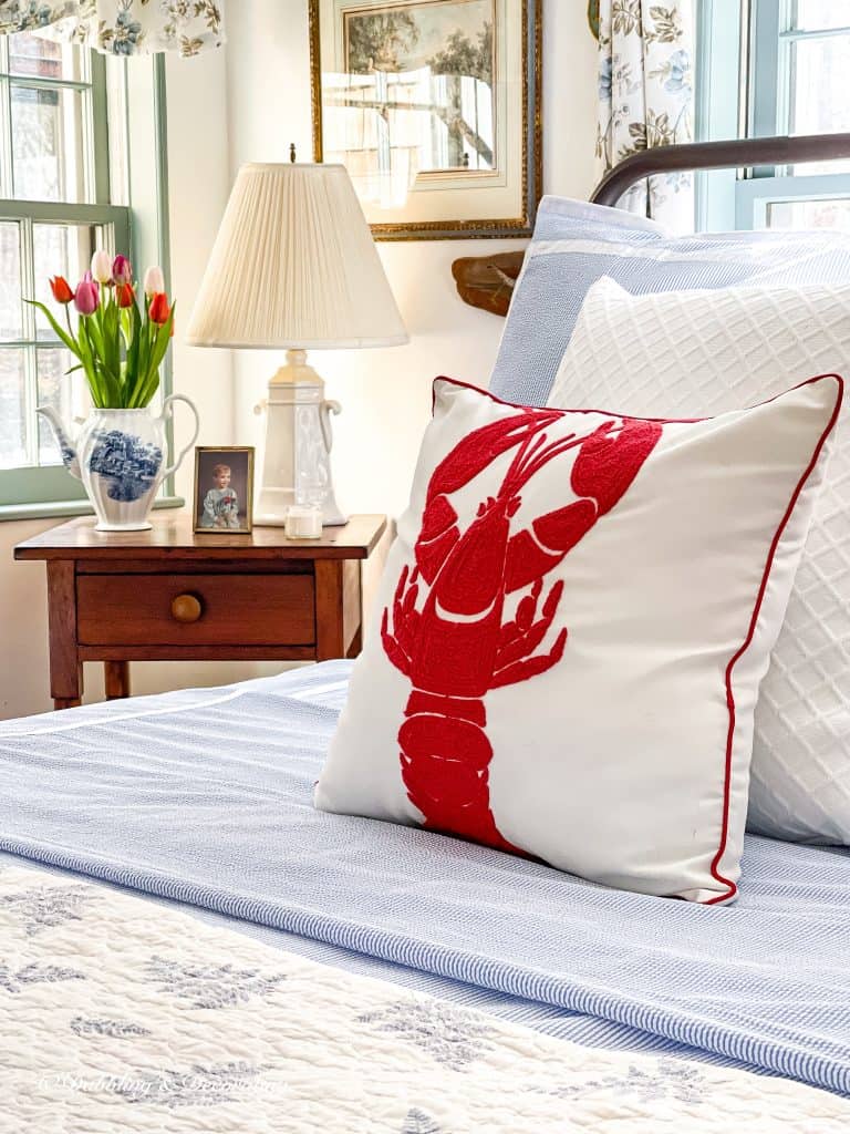 Coastal Bedroom with lobster pillow and bedside table with spring tulips.