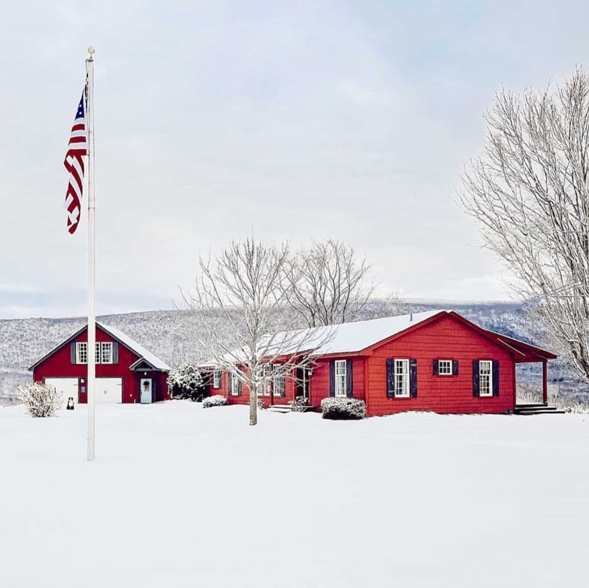 A red house with year-round mountain views in the snow.