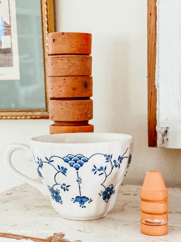 teacup with terracotta pots on mantel.