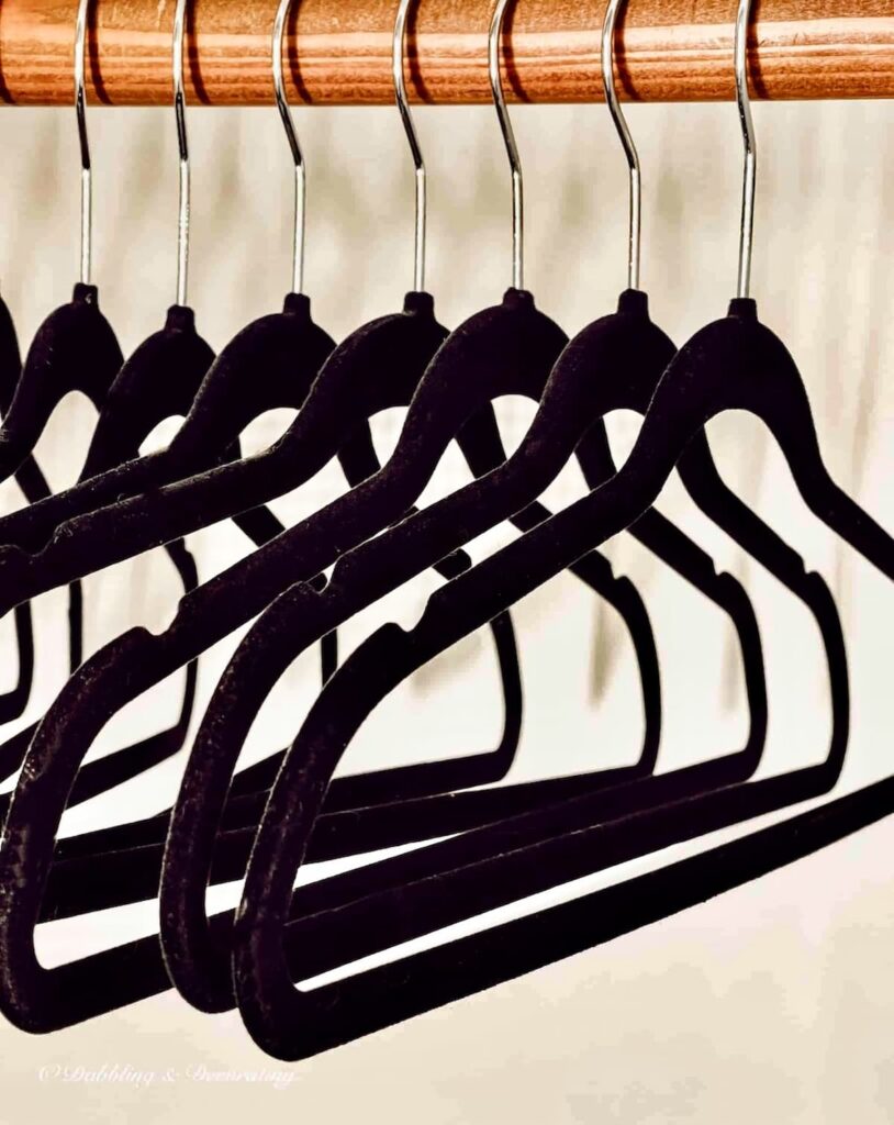 Thrifted black velvet hangers hanging in closet.