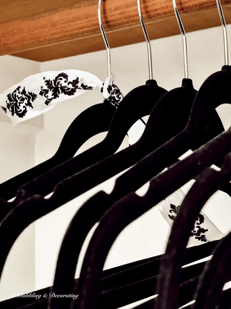 Black velvet clothes hangers in closet with black and white ribbon close up.