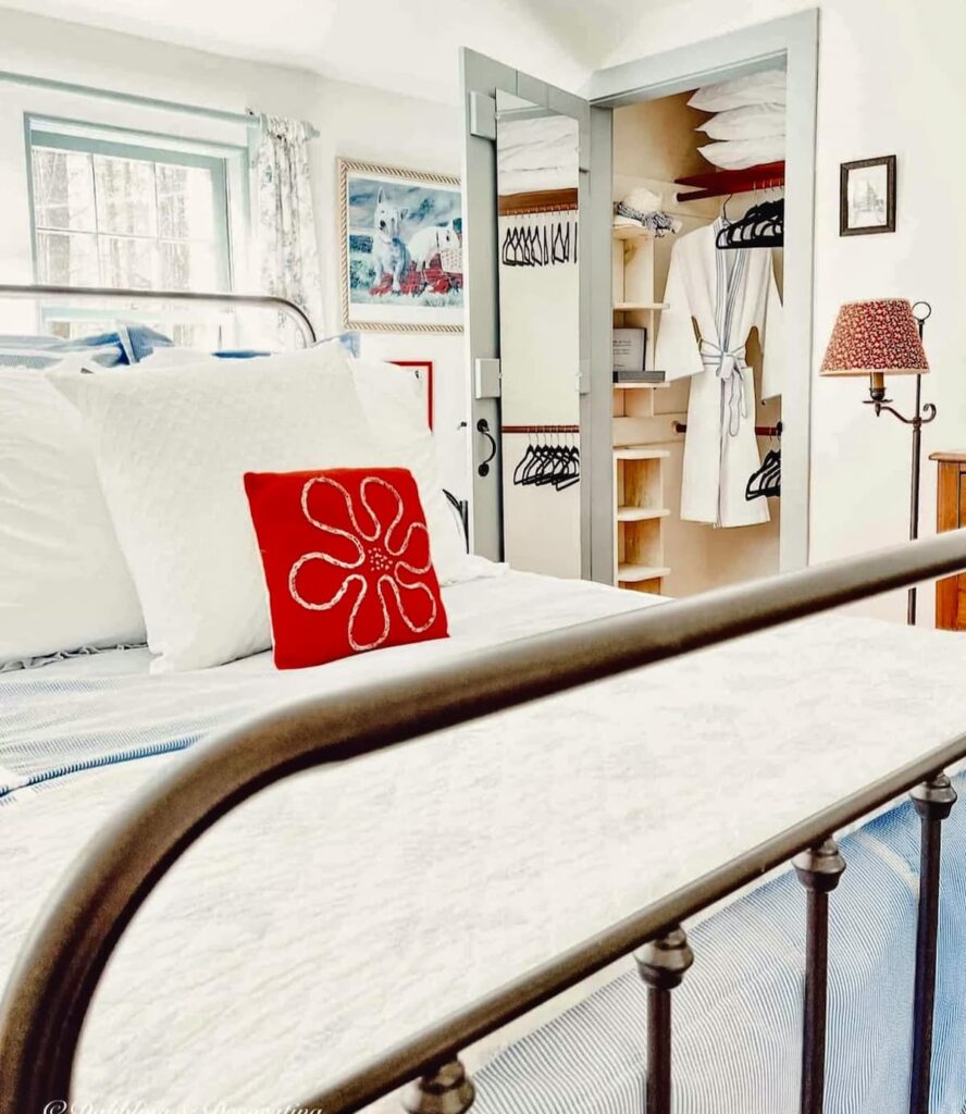 Wrought iron bed in small vintage style guest bedroom with open closet.