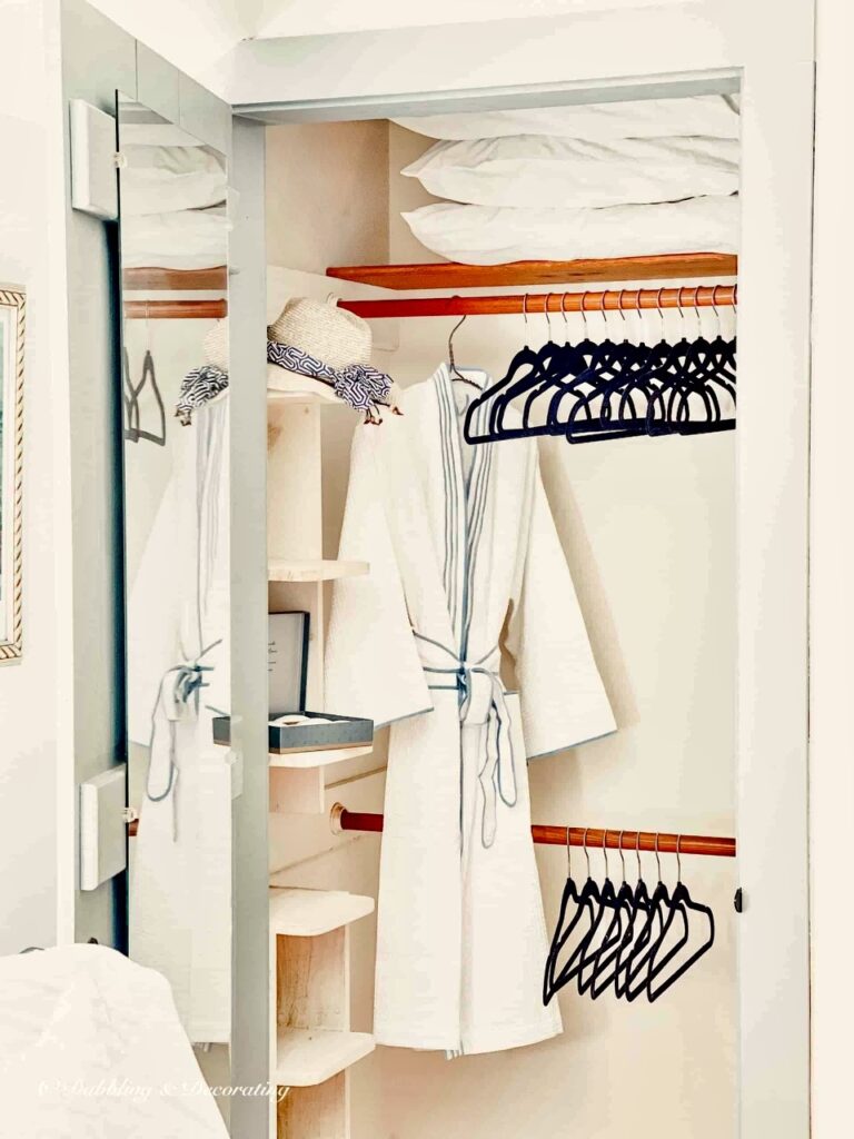 Open closet with bathrobe and velvet hangers in small guest bedroom.