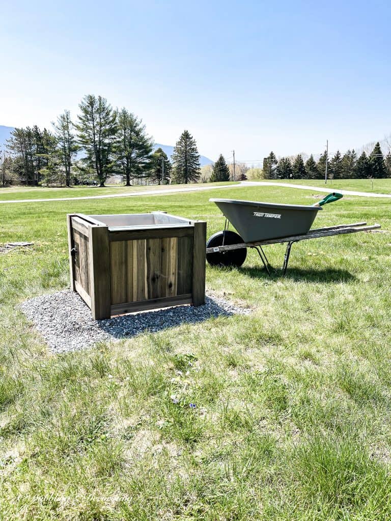 Wooden Fire Pit and Wheelbarrow on top of a grass covered field