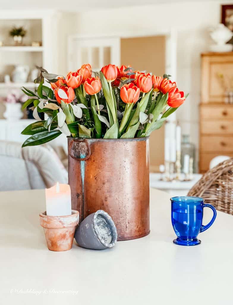 Copper bucket with orange tulip arrangement.