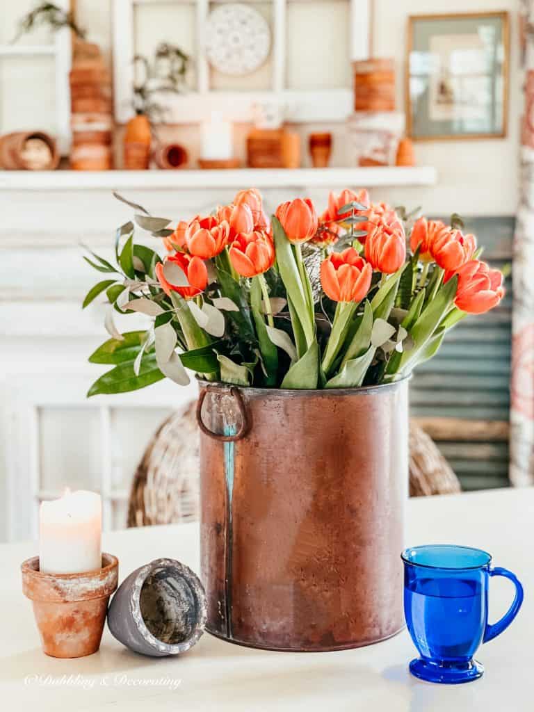 Spring orange tulips in copper bucket and terracotta pots.