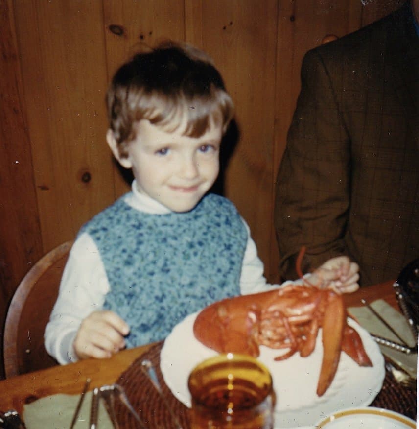 Child with Lobster and vintage lobster utensils at dining table.