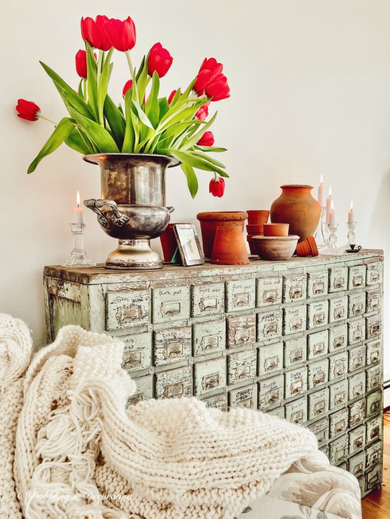 Tulip arrangement with garden pots indoors on vintage apothecary cabinet