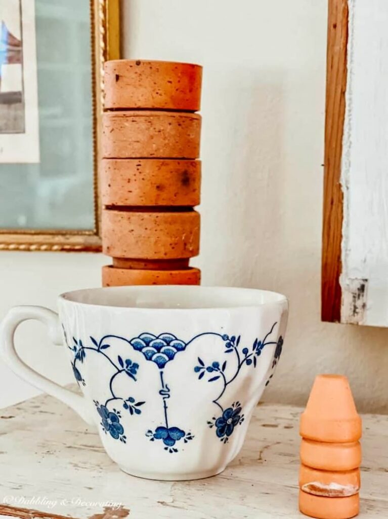 Vintage blue and white tea cup and stack of small terracotta pots.