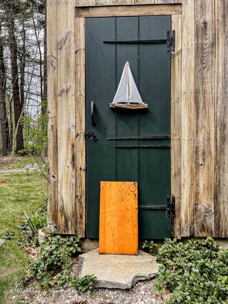 A green wooden door with a sailboat and a child\'s desktop