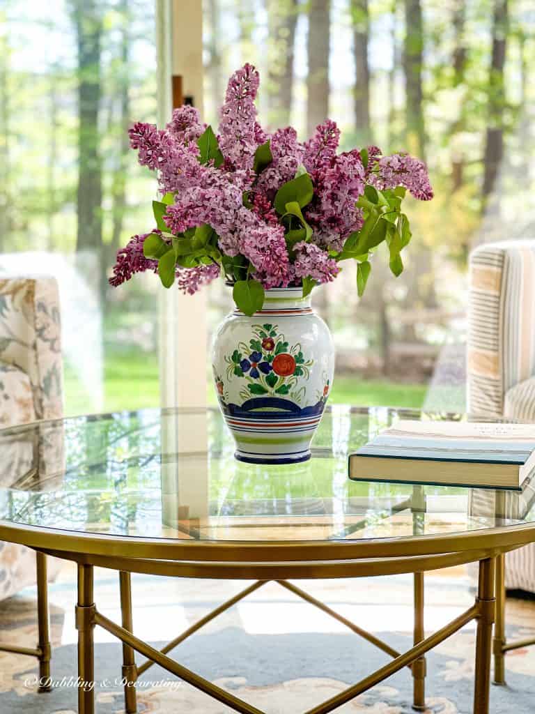 Purple Lilacs centerpiece on glass table.